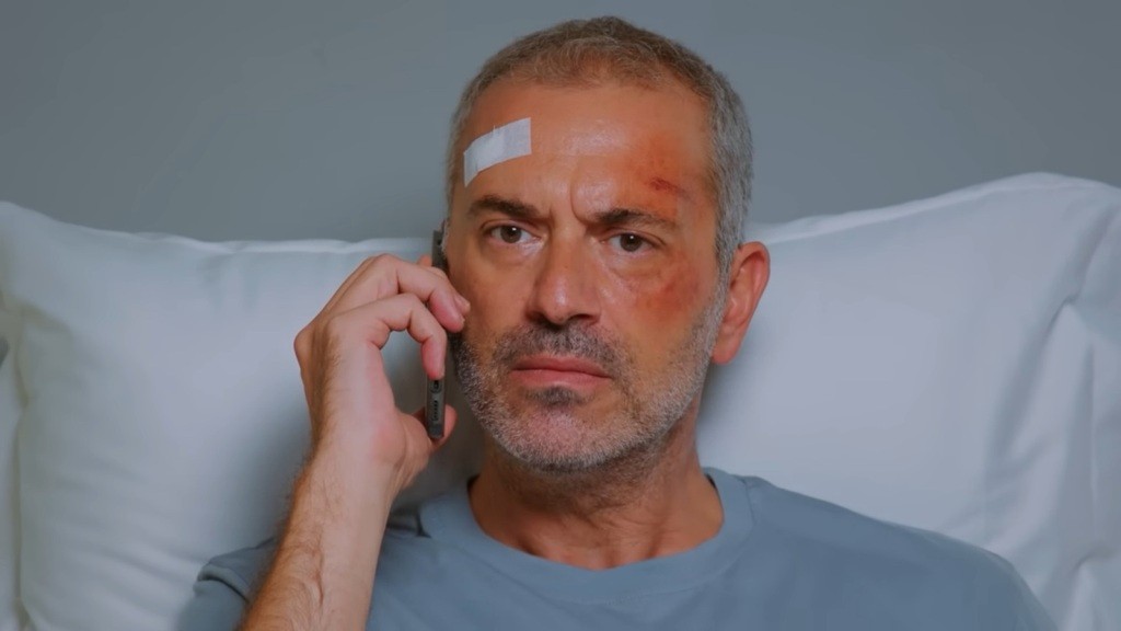 Leżący na szpitalnym łóżku Bulent rozmawia przez telefon.