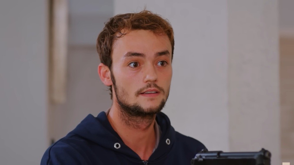 Alper trzyma w ręku pistolet.