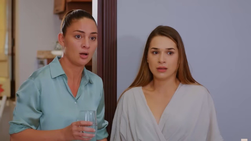 Yildiz trzyma w ręku szklankę z wodą, zaskoczona sytuacją. Obok niej stoi Sila.