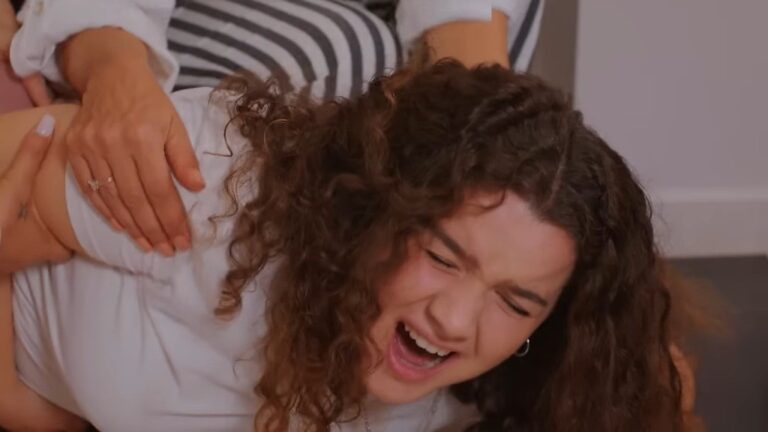 Melis zwija się z bólu, trzymając się za brzuch.