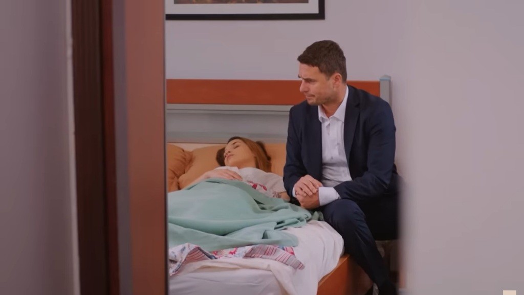 Kuzey siedzi przy łóżku Sili, trzymając jej dłoń.