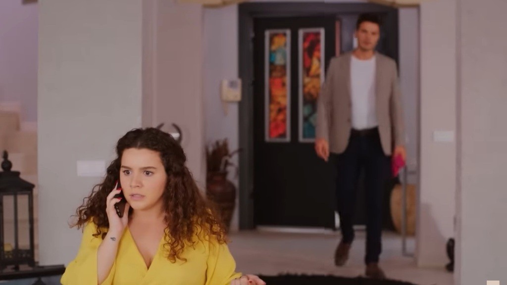 Melis rozmawia przez telefon, nie zdając sobie sprawy, że za jej plecami zbliża się Ege.