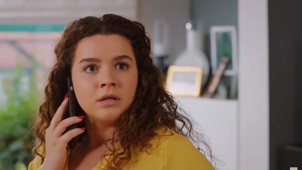 Melis odwraca głowę, trzymając telefon przy uchu. Na jej twarzy maluje się przestraszony wyraz.