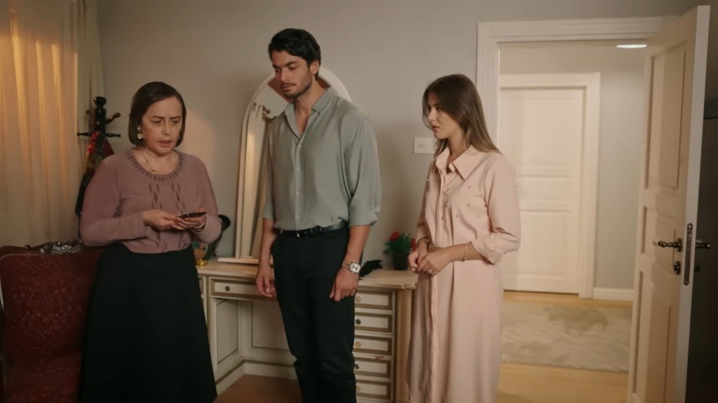 Kiymet trzyma w rękach telefon. Obok niej stoją Eren i Selma.