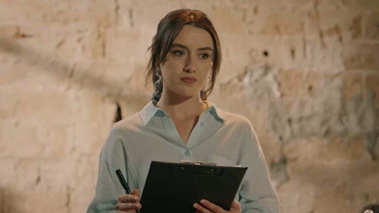 Zeynep trzyma w rękach notatnik i długopis.