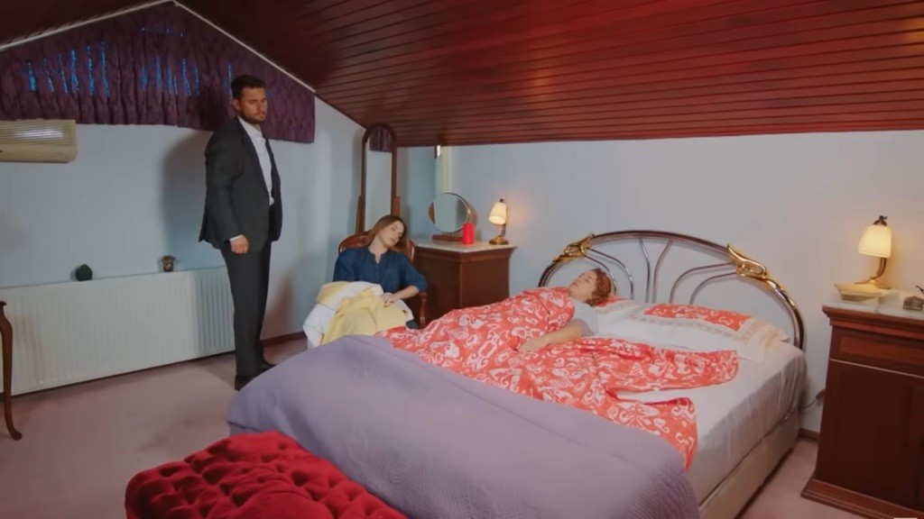 Kuzey stoi w pokoju siostry, która śpi na łóżku. Sila zasnęła w fotelu.