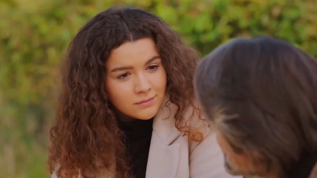 Melis patrzy na Taylana, siedząc obok niego.