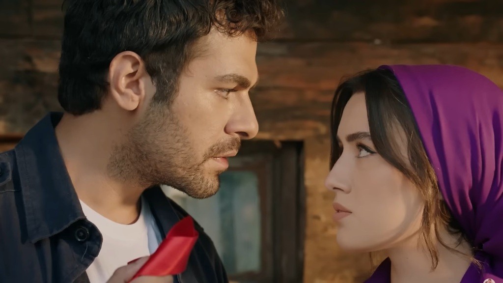 Halil trzyma w ręku czerwoną wstążkę i patrzy w oczy Zeynep.