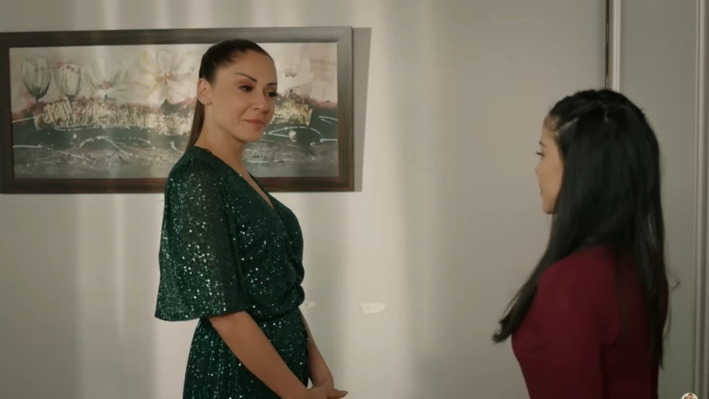 Kumru ma na sobie zieloną sukienkę, która lśni dzięki licznym cekinom, dodając jej wyjątkowego blasku i elegancji. Przed nią stoi Merve.