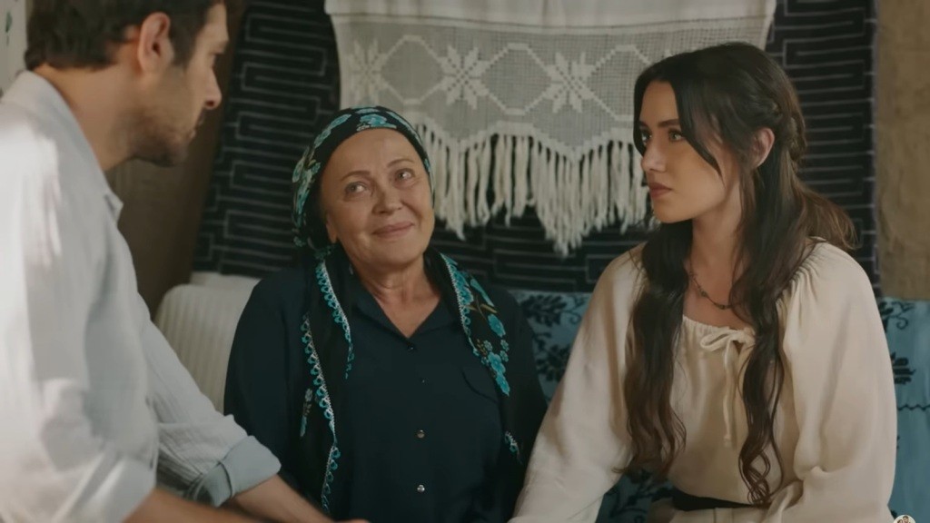 Zumrut patrzy z ciepłem w oczach na Halila i Zeynep, którzy siedzą naprzeciwko siebie, trzymając się za ręce.
