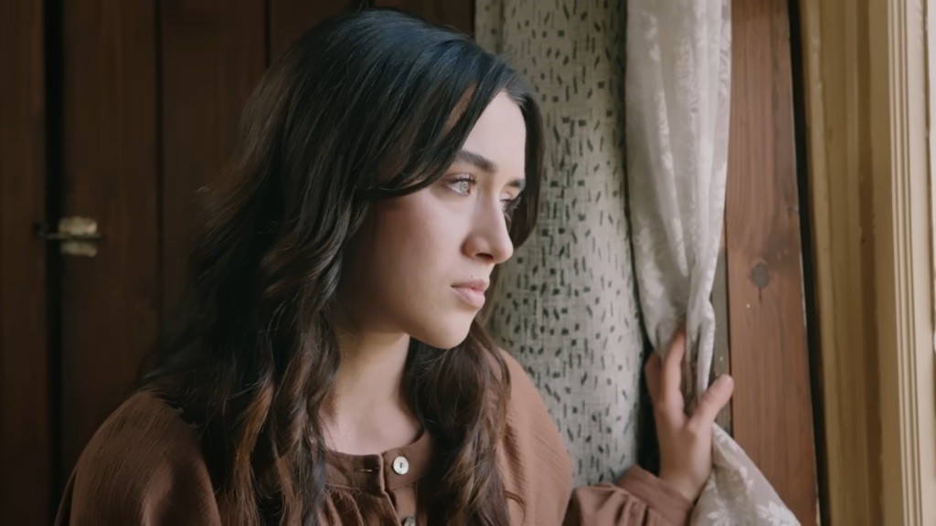 Zeynep odchyla firankę i wygląda przez okno.