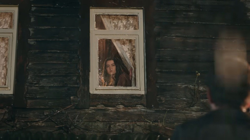 Zeynep spogląda przez okno na podwórze, gdzie stoi Halil.