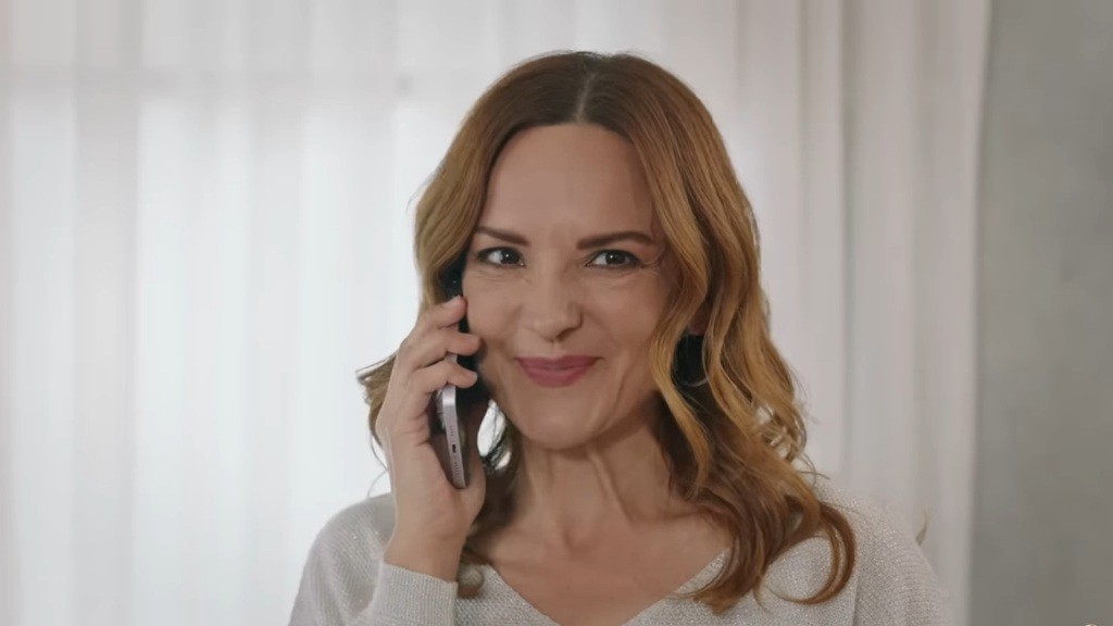 Songul uśmiecha się, rozmawiając przez telefon.