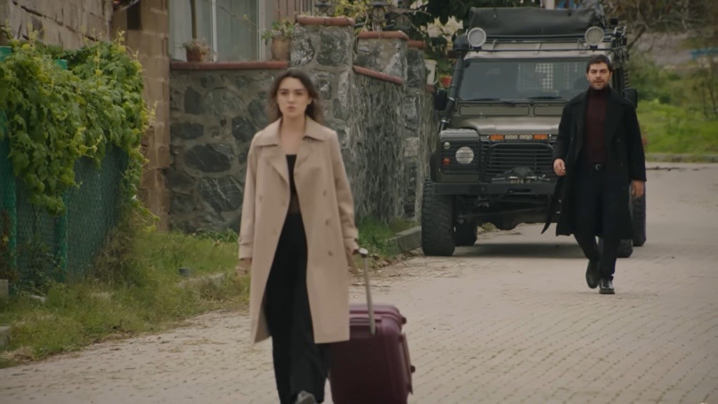 Zeynep odchodzi, ciągnąc za sobą walizkę. Halil znajduje się kilka metrów za nią.