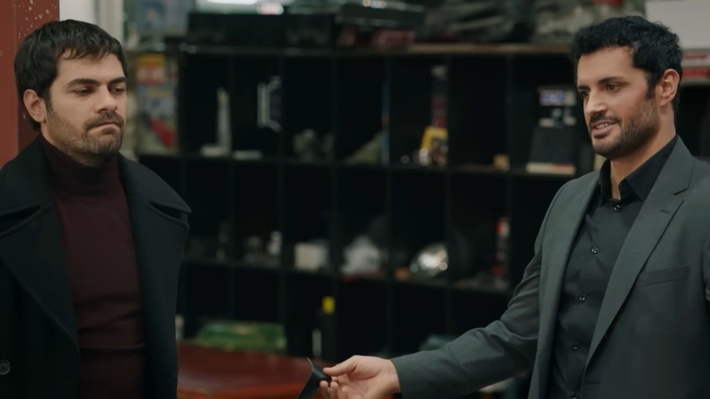 Halil jest przywiązany do słupa, a Sadik stoi obok niego.