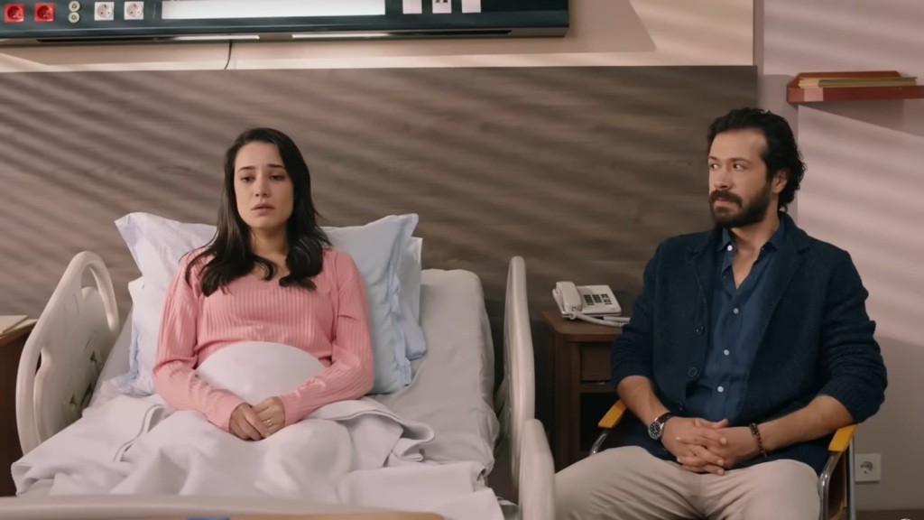 Gulhan siedzi na szpitalnym łóżku. Obok, w fotelu, siedzi Tekin. Oboje są przygnębieni.