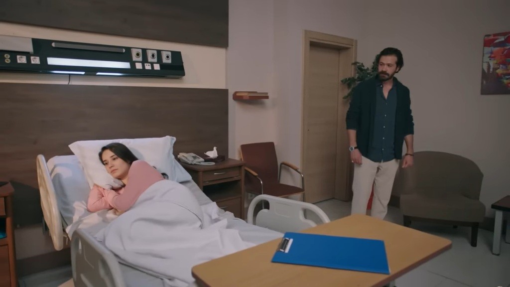 Gulhan leży na szpitalnym łóżku, odwrócona plecami do męża.
