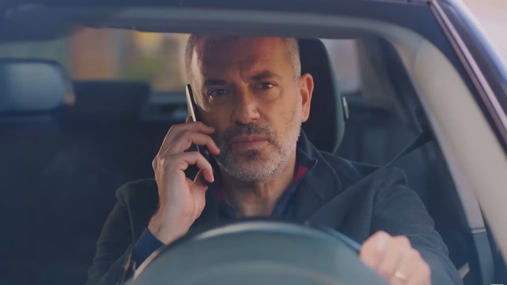 Bulent siedzi za kierownicą i rozmawia przez telefon.