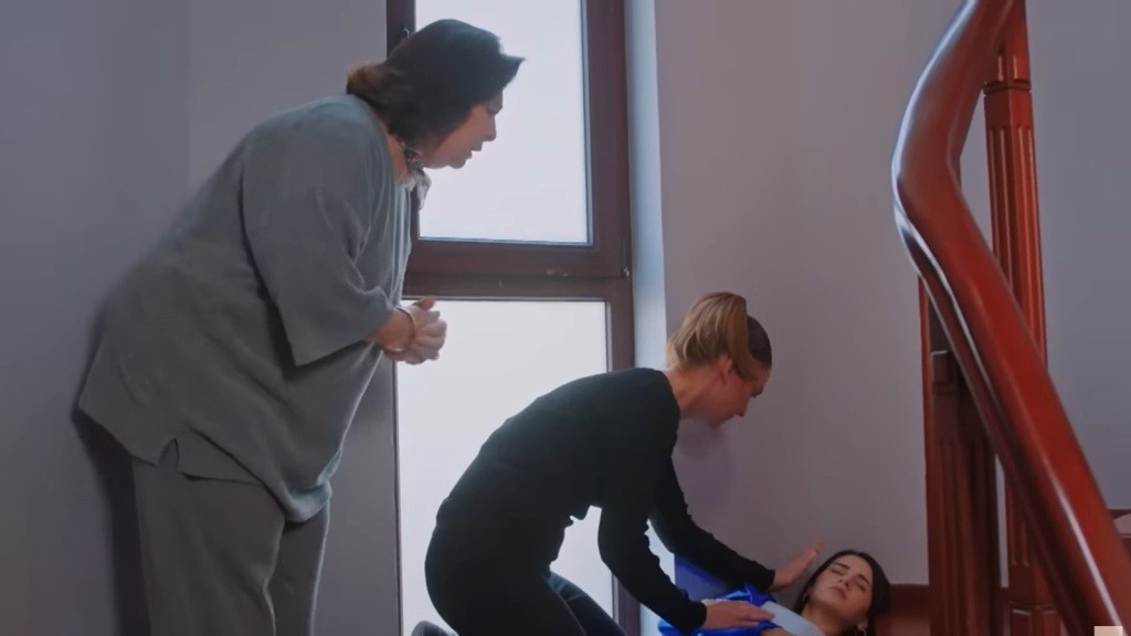 Yildiz pochyla się nad leżącą na schodach Bahar. Tuż za nią stoi Naciye i z niepokojem patrzy na nieprzytomną Bahar.