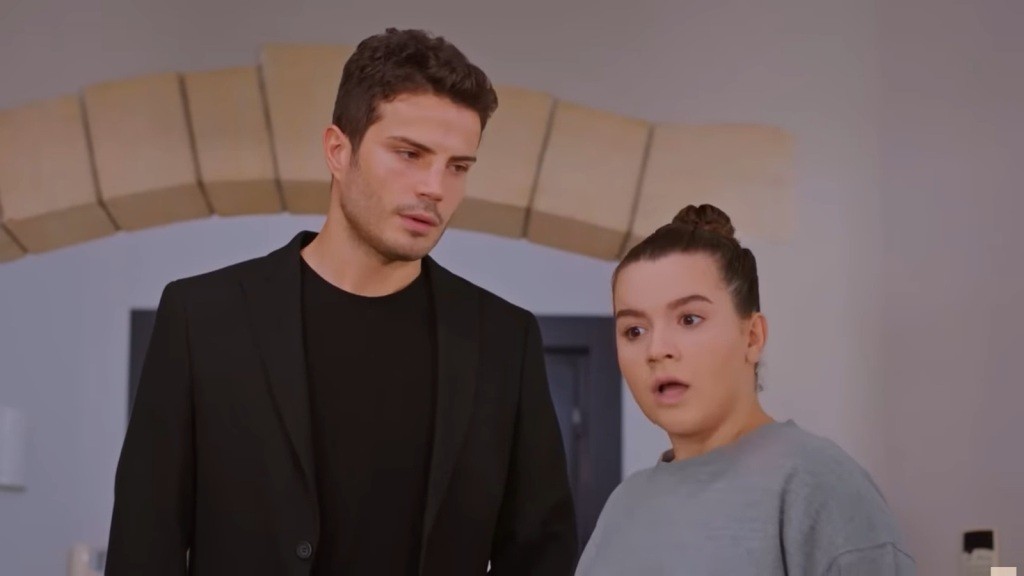 Melis spogląda z mieszanką oburzenia i niedowierzania. Obok niej stoi Ege.