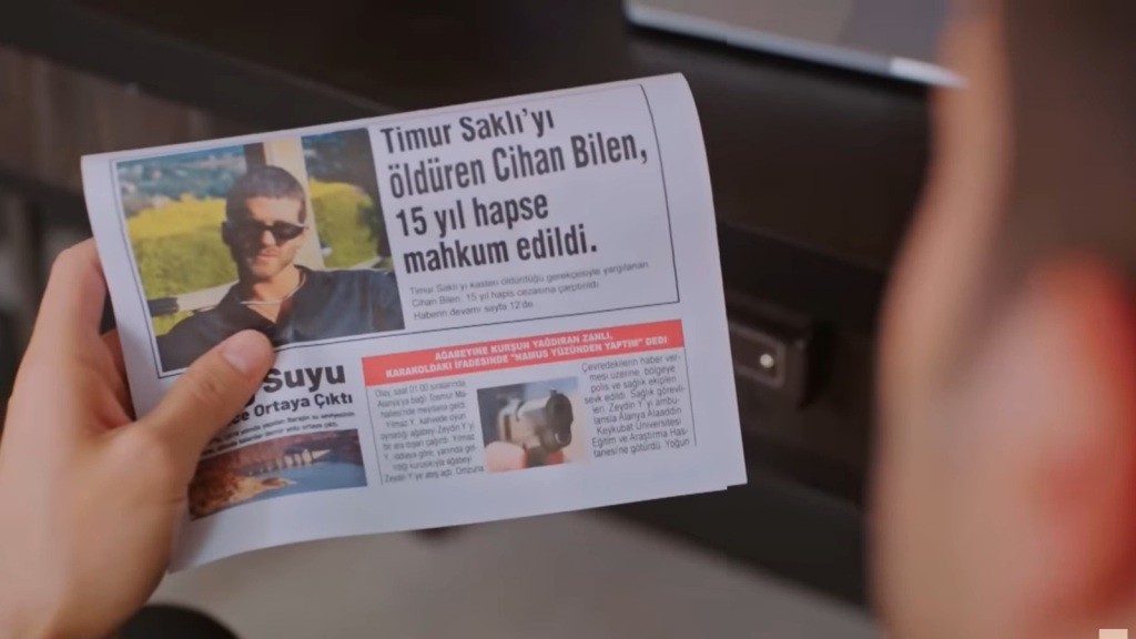 Wydrukowana strona z gazety w rękach Egego. Widnieje na niej informacja o skazaniu Cihana za morderstwo.