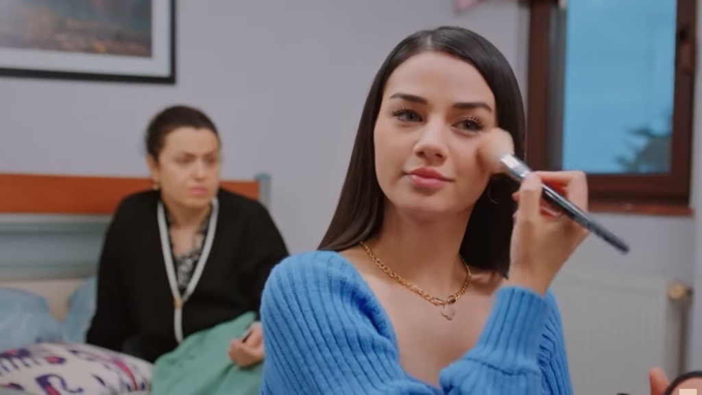 Bahar maluje się. Za nią siedzi jej matka.