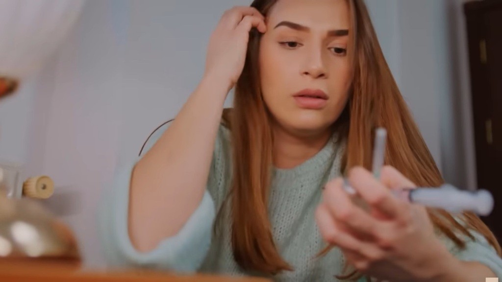 Sila jednym ruchem odgarnia włosy za ucho, podczas gdy w drugiej ręce trzyma strzykawkę oraz ampułkę.