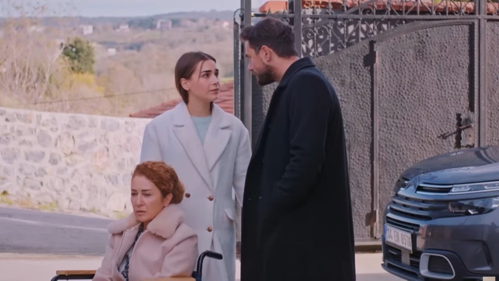 Scena na podwórku. Hulya siedzi na wózku inwalidzkim. Obok stoją Sila i Kuzey, wpatrzeni w siebie.