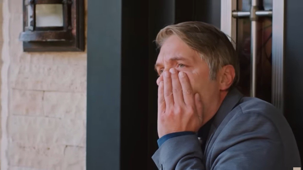 Tahir trzyma się za policzek, w który został uderzony.