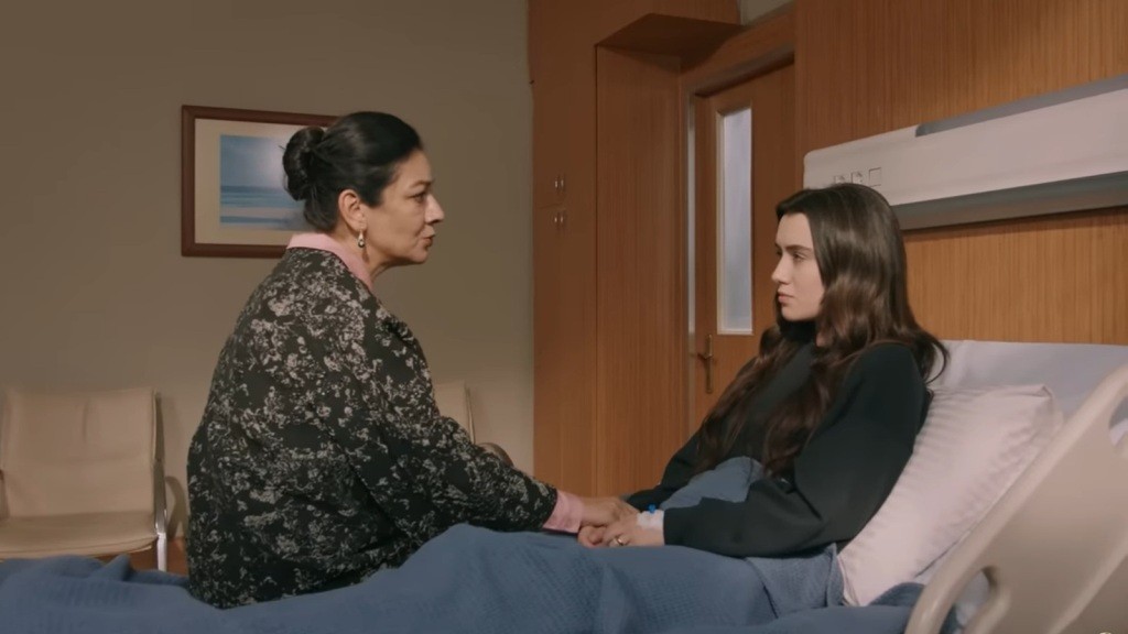 Tulay siedzi przy Zeynep, trzymając ją za ręce.