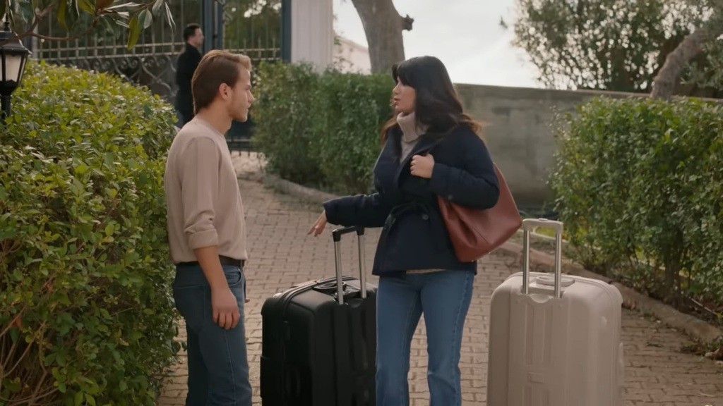 Gozde opiera się o rączkę walizki, rozmawiając z Cemilem.