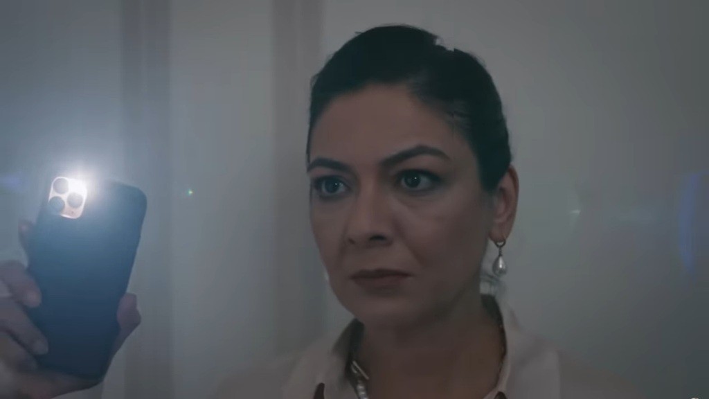 Tulay trzyma w ręku latarkę i patrzy z napięciem.