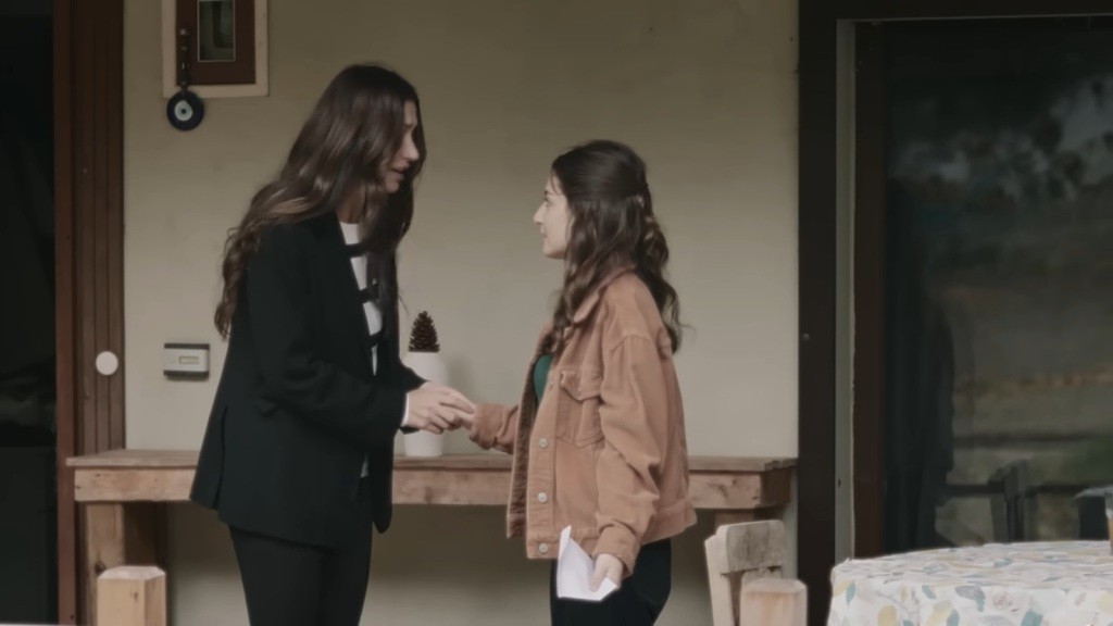 Scena z retrospekcji. Songul trzyma rękę nastoletniej Gozde, rozmawiając z nią.