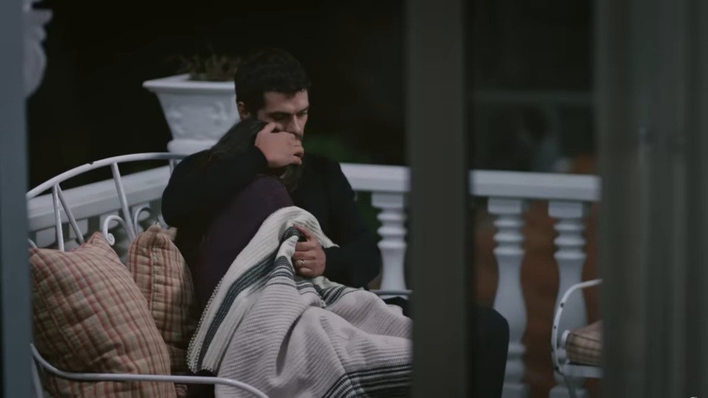 Halil i Zeynep siedzą na ławce na tarasie, wtuleni w siebie.