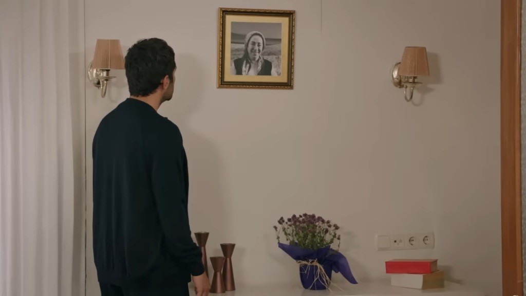 Halil patrzy na zdjęcie swojej mamy na ścianie.