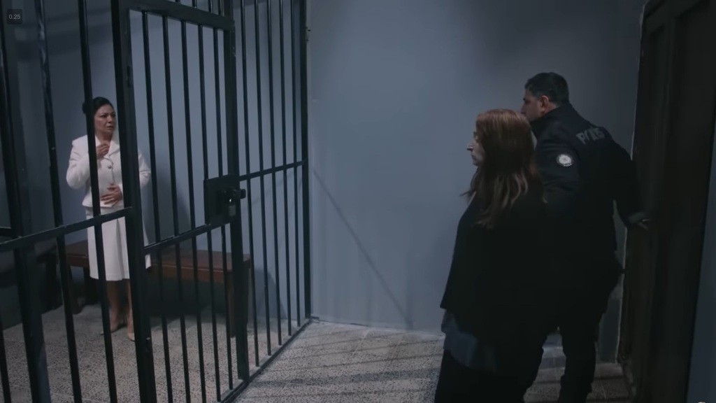 Strażnik prowadzi nową osadzoną do celi Tulay.