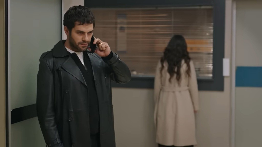 Halil rozmawia przez telefon. Przed szybą sali Tulay stoi Zeynep.