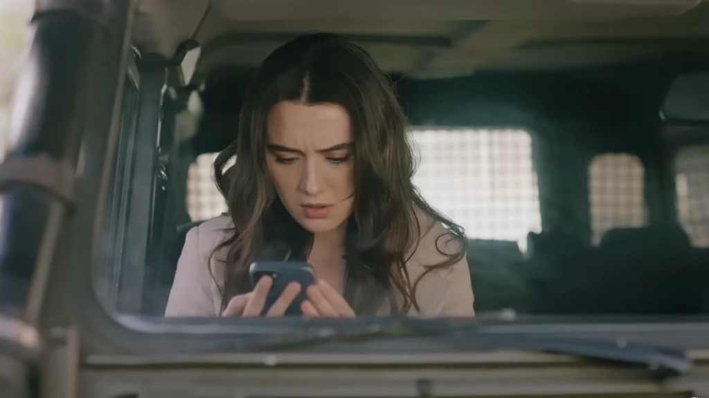 Zeynep siedzi na fotelu pasażera w samochodzie Halila. Z niepokojem wpatruje się w ekran telefonu.