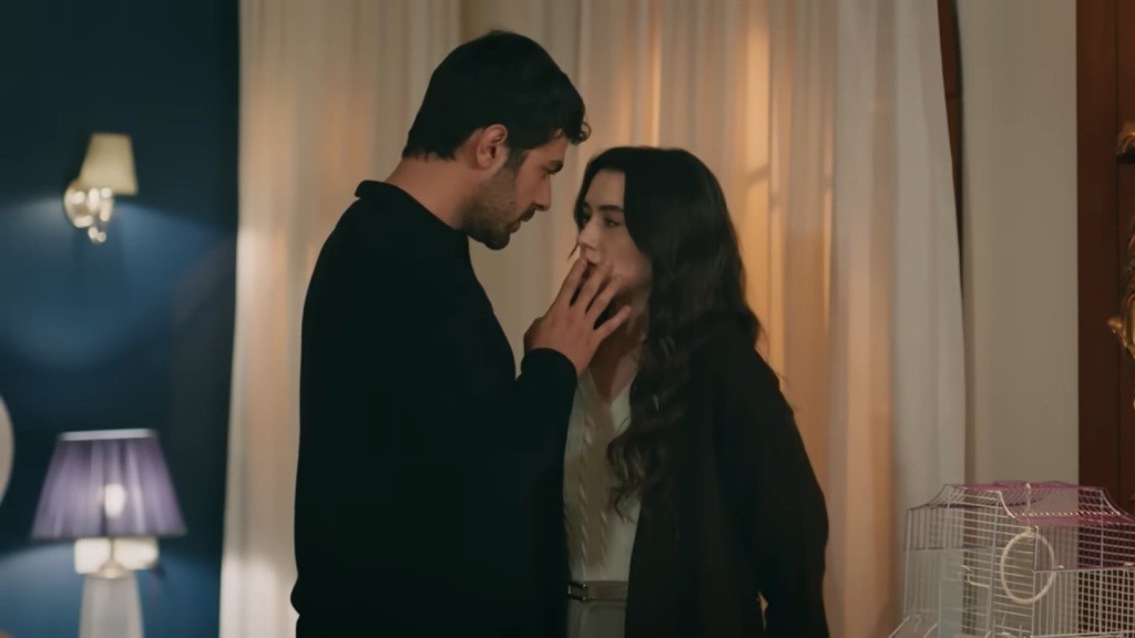 Halil stoi przed Zeynep i palcami zasłania jej usta.