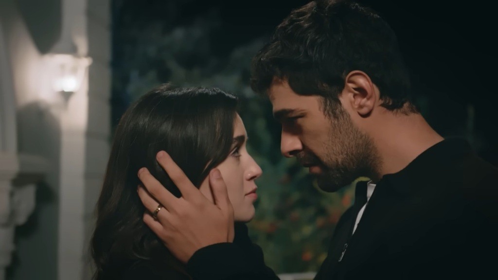 Halil obejmuje dłońmi głowę Zeynep, stojąc naprzeciwko niej na tarasie.