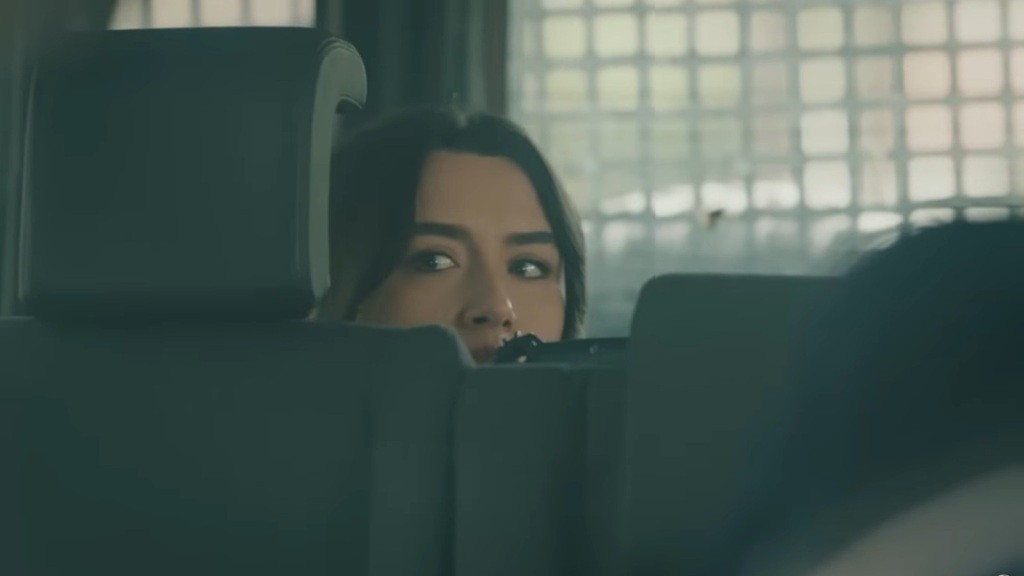 Zeynep wygląda zza tylnego rzędu fotelu w samochodzie Halila.
