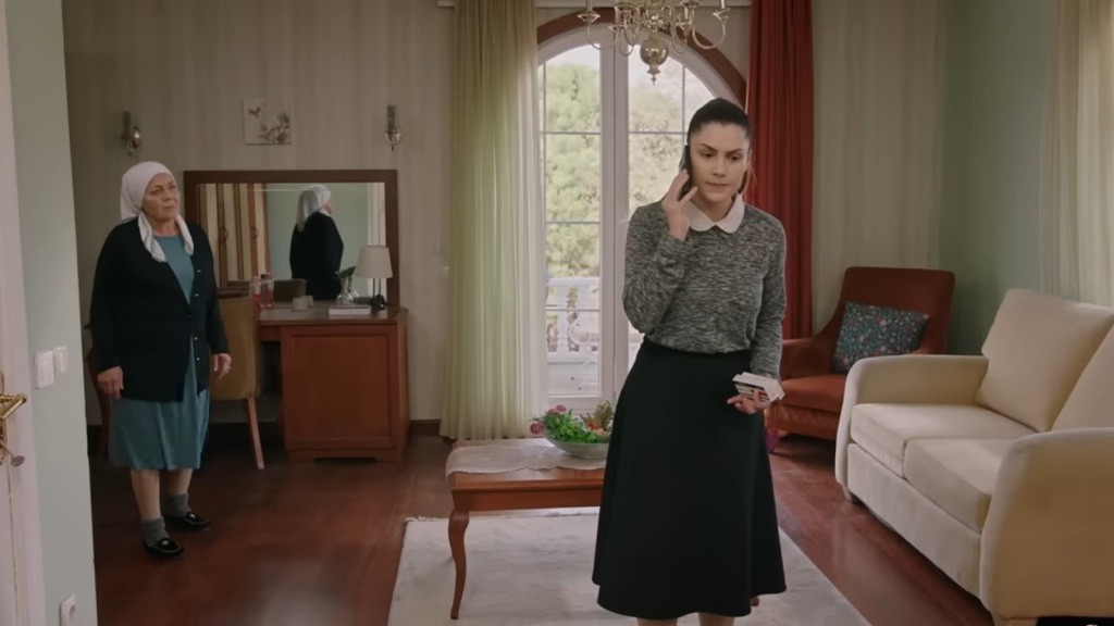 Arzu rozmawia przez telefon, nieświadoma, że za jej plecami stoi Zumrut i wszystko słyszy.