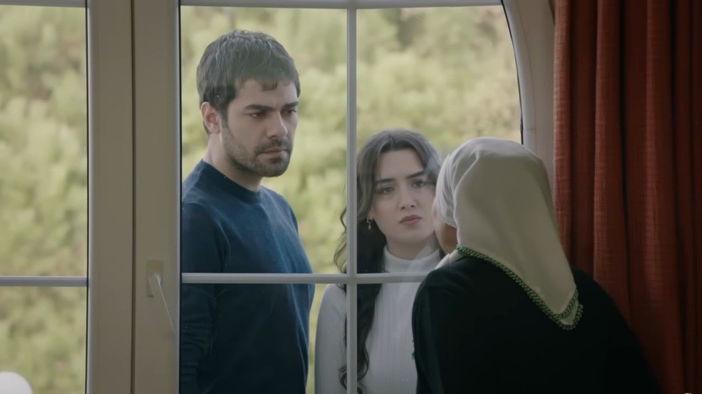 Zeynep i Halil stoją za drzwiami balkonowymi i proszą, by Zumrut wpuściła ich do środka.