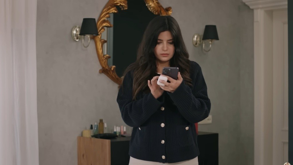 Blada na twarzy Gozde wpatruje się w ekran telefonu.