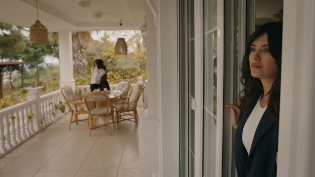 Gözde podsłuchuje rozmowę Selmy i Zeynep, ukryta za otwartymi drzwiami balkonowymi na werandzie.
