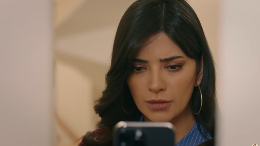 Gozde patrzy w ekran telefonu.