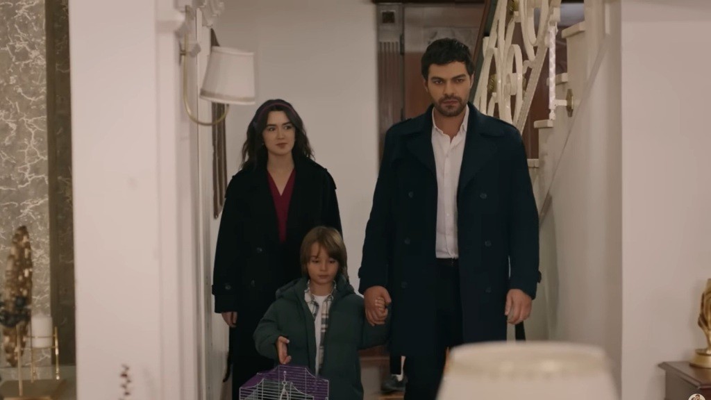 Halil trzyma Ardę za rękę, a obok nich idzie Zeynep. Razem zmierzają do salonu.