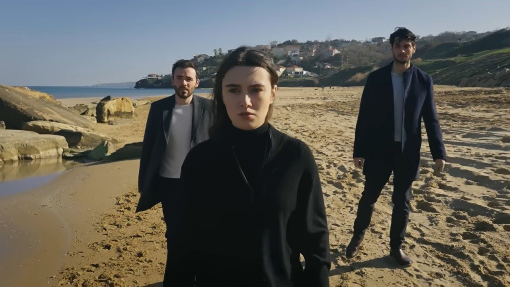 Zeynep, Hakan i Eren idą brzegiem morza.