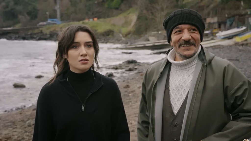 Zeynep i Yunus stoją obok siebie i patrzą w jednym kierunku. Zeynep sprawia wrażenie zaskoczonej, a mężczyzna uśmiecha się z zadowoleniem.