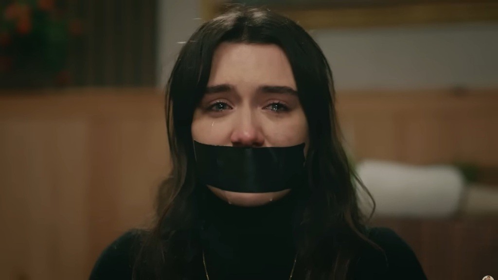Zbliżenie na twarz Zeynep: jej usta są zakneblowane, a oczy błyszczą od łez.